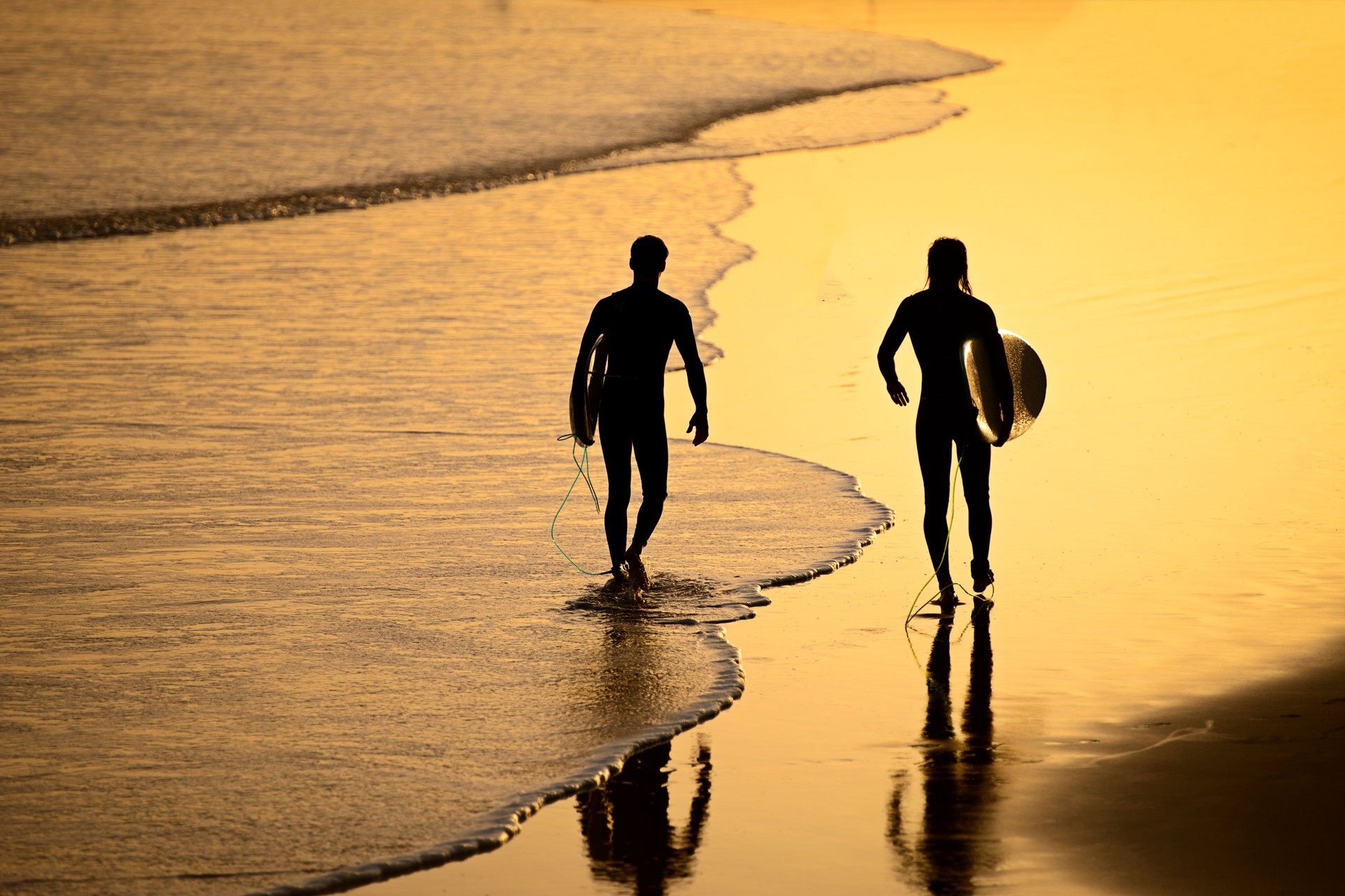 surfers goes to ride a board on the Moroccan coast of the Atlantic Ocean at sunset